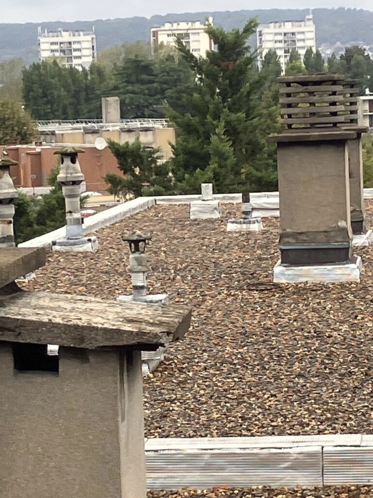 Toiture-terrasse gravillonnée d'un immeuble en copropriété, avec souches de ventilation et édicule technique